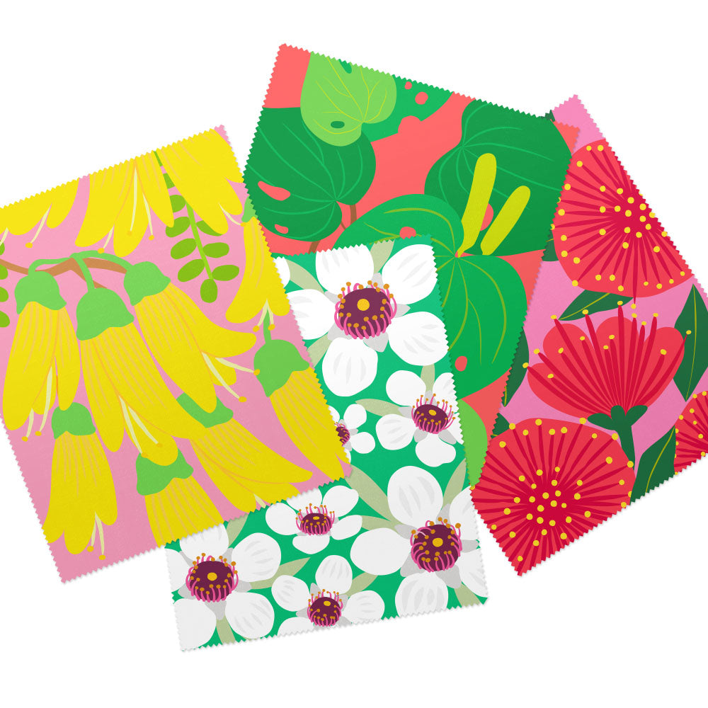 The Set of 4 Bright Botanical Collection Lens Cloths features rectangular cloths with colorful floral designs: yellow flowers on pink, green and red leaves, white flowers on green, and red flowers on pink backgrounds.
