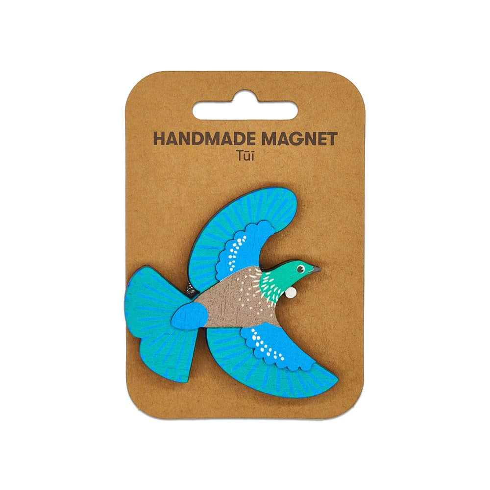 The Tui Wooden Magnet is a handmade piece shaped and painted as a tui bird with blue wings, brown body, and green head, attached to a HANDMADE MAGNET Tūī card—a charming example of Kiwiana.