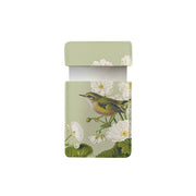 The Birds Botanics Rifleman Pocket Mirror is a small, rectangular, light green vegan leather case with a flap lid, featuring a yellow-green rifleman bird on a branch among white flowers and green leaves—a charming accessory.