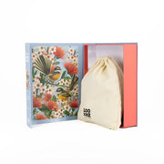 An open Native Flowers and Chatty Fantails Jigsaw Puzzle Box displays a cream drawstring bag with “LOO NZOO” partially visible, ideal for storing your 1000-piece puzzle—set against a white background.