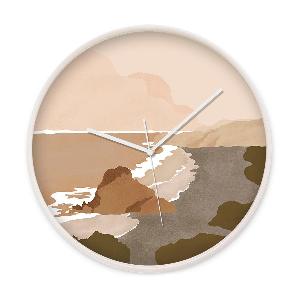 The Piha Landmark Wooden Frame Clock features a round design with a minimalist abstract coastal landscape in beige, brown, and green, inspired by New Zealand. It has three white hands, silent movement, and a numberless face.