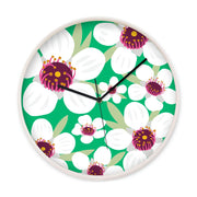 The Bright Botanical Manuka Wooden Frame Clock features a silent movement and a green background with white flowers, dark pink centers, and yellow accents—a vibrant design inspired by New Zealand’s natural beauty.