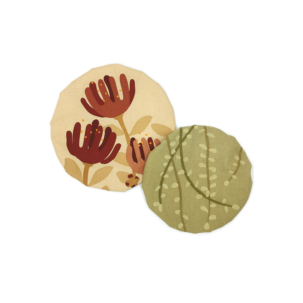 Two round paper coasters—one beige with a red flower, the other smaller green with a light vine pattern—overlap on white, perfectly complementing Raw Bowl Covers (set of 2) with cotton outer for stylish food storage.