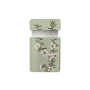 A light green rectangular vegan leather Vintage Botanical Manuka Pocket Mirror case with a flap, featuring a branch of white flowers and green leaves, shown open with a white card partially visible inside.