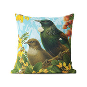 The Botanical Tui Cushion Cover features two birds on a branch with yellow flowers and green leaves against a light blue background. Made from durable polyester, it's ideal for both indoor and outdoor use.