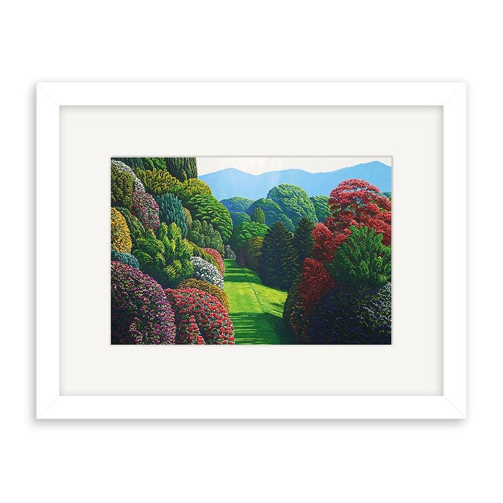 The Karl Maughan - Marchent Ridge Small Art Print: Second Frame features green trees, red and purple bushes, a grassy path, and distant mountains. Its white frame contrasts beautifully with the vibrant landscape.