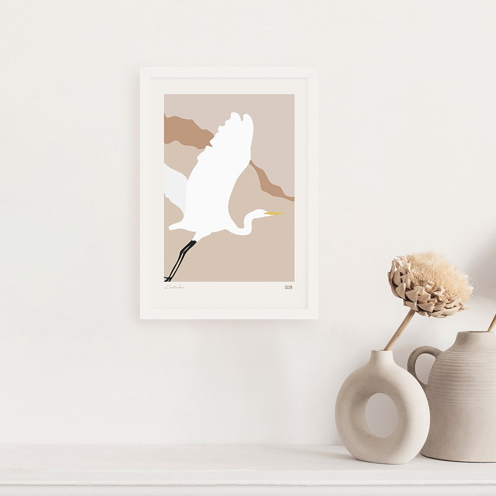 The Modern Heron Print, a framed minimalist archival artwork featuring a white heron in flight, adds simple decor above a shelf with neutral-toned vases and dried flowers, celebrating native birds.