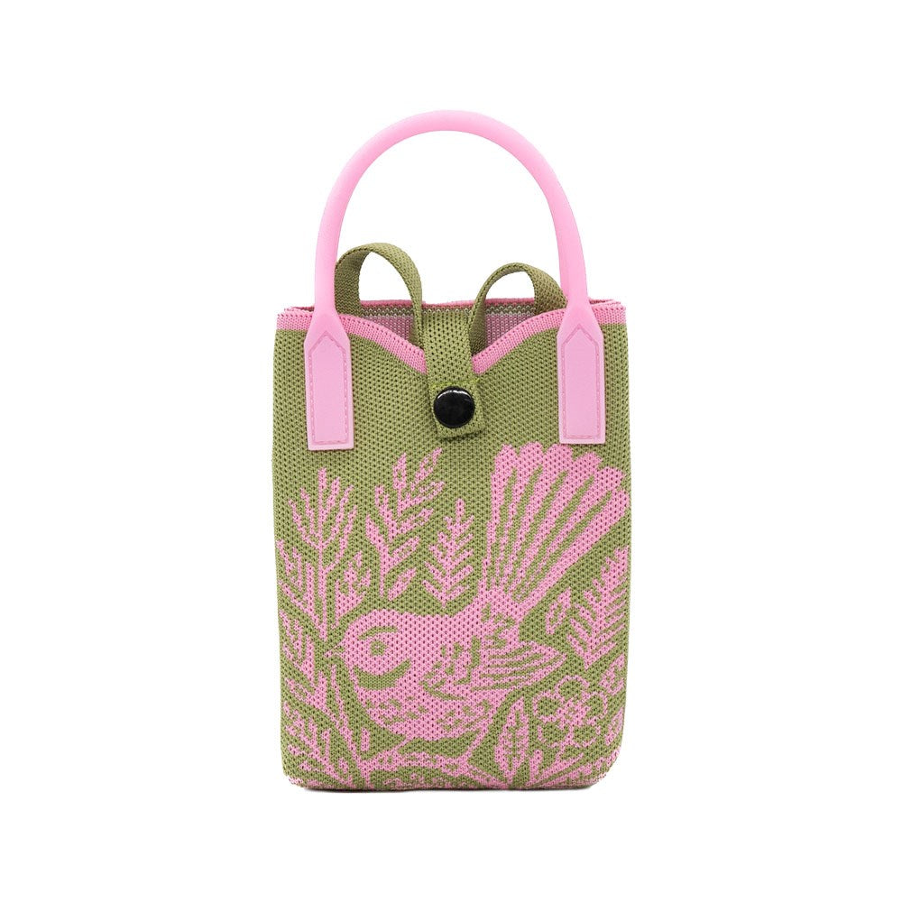 The Fantail Woodcut Cross-body Bag is a small, rectangular, lightweight bag in olive green fabric with pink handles, trim, black button closure, and a pink woven native bird and foliage design on the front.