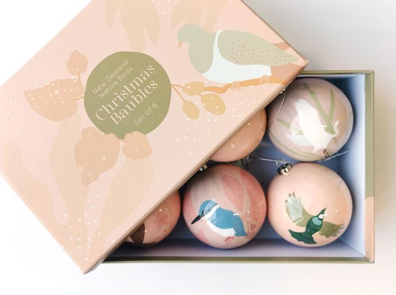 A box labeled Modern Native Bird Christmas Baubles – Second contains six round ornaments, each adorned with pastel-colored illustrations of birds. Inspired by native New Zealand birds, the baubles and box showcase soft pink and green tones with nature-inspired designs, making this gift set a charming addition to your Christmas decorations.
