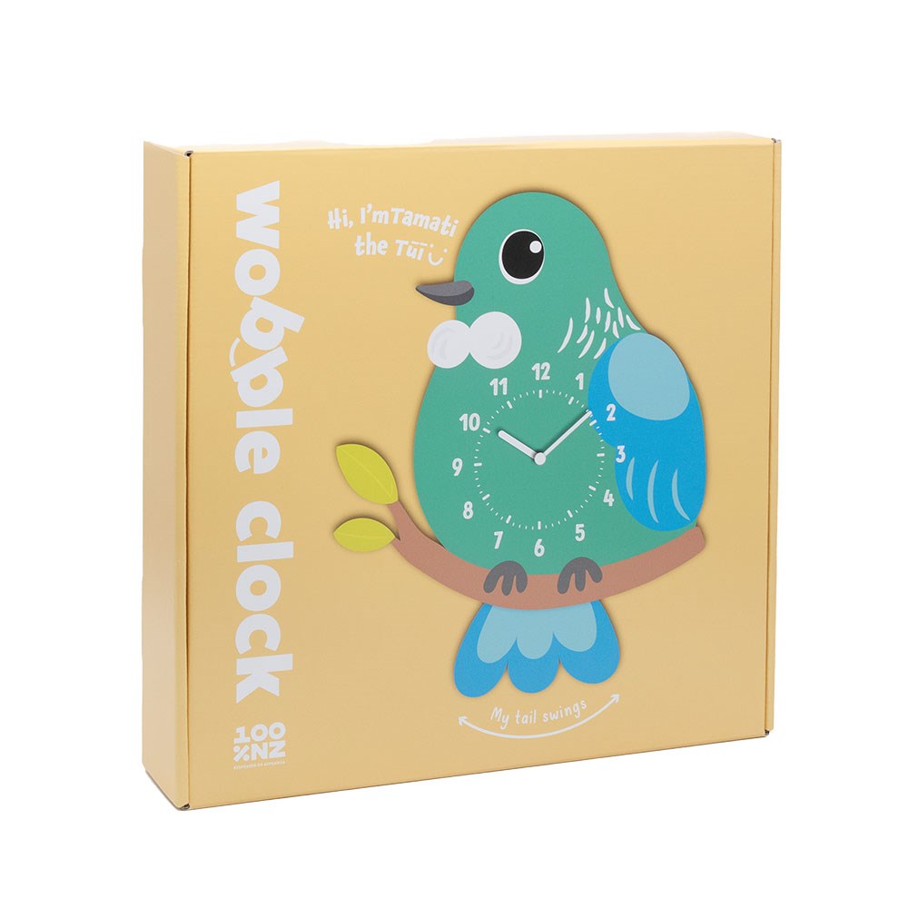 A yellow box displays the Tui Kids Wobble Clock, shaped like a cartoon blue and green bird on a branch. The clock face is on its belly, with a swinging tail and “Hi, I’m Tamati the Tūī” and “wobble clock” on the packaging.