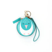 The Kereru Cutie Coin Purse is a round turquoise purse with a bird face, pink beak, and white chest. It includes a matching wrist strap and gold keyring—ideal for bird lovers and style enthusiasts on the move.