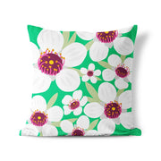 The Bright Botanical Manuka Cushion Cover features a green background with large white flowers, purple and yellow centers, and green leaves on durable polyester—perfect for stylish indoor or outdoor decor.