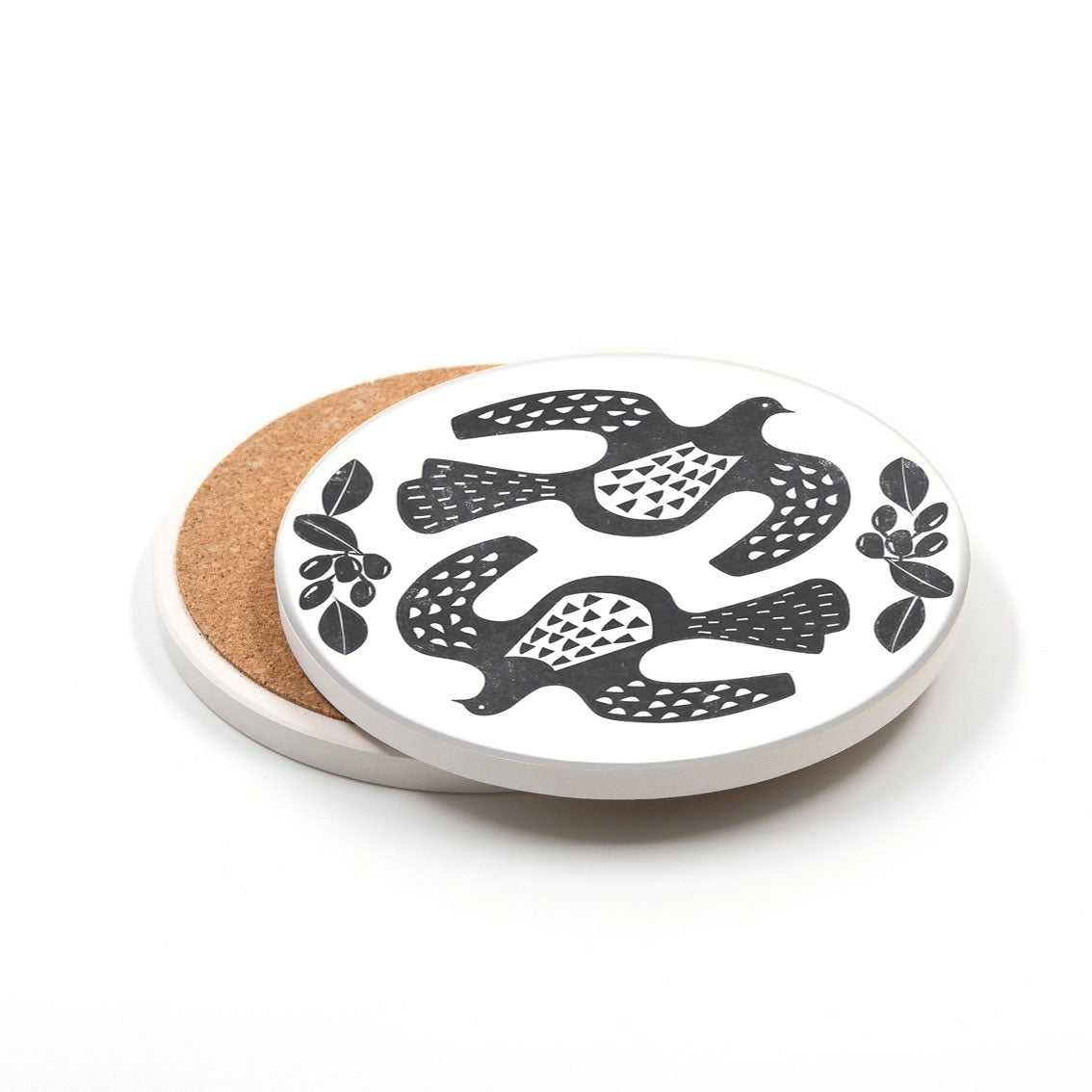 A Set of 3 Linocut Ceramic Coasters with cork backing, printed in New Zealand, featuring black and white illustrations of stylized birds and leaf motifs. Another coaster is partially visible underneath.