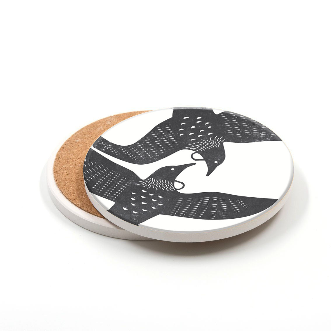 A set of 3 round ceramic coasters features black and white linocut-style illustrations of two overlapping birds in flight on a white background, with visible cork backing. Printed in New Zealand.