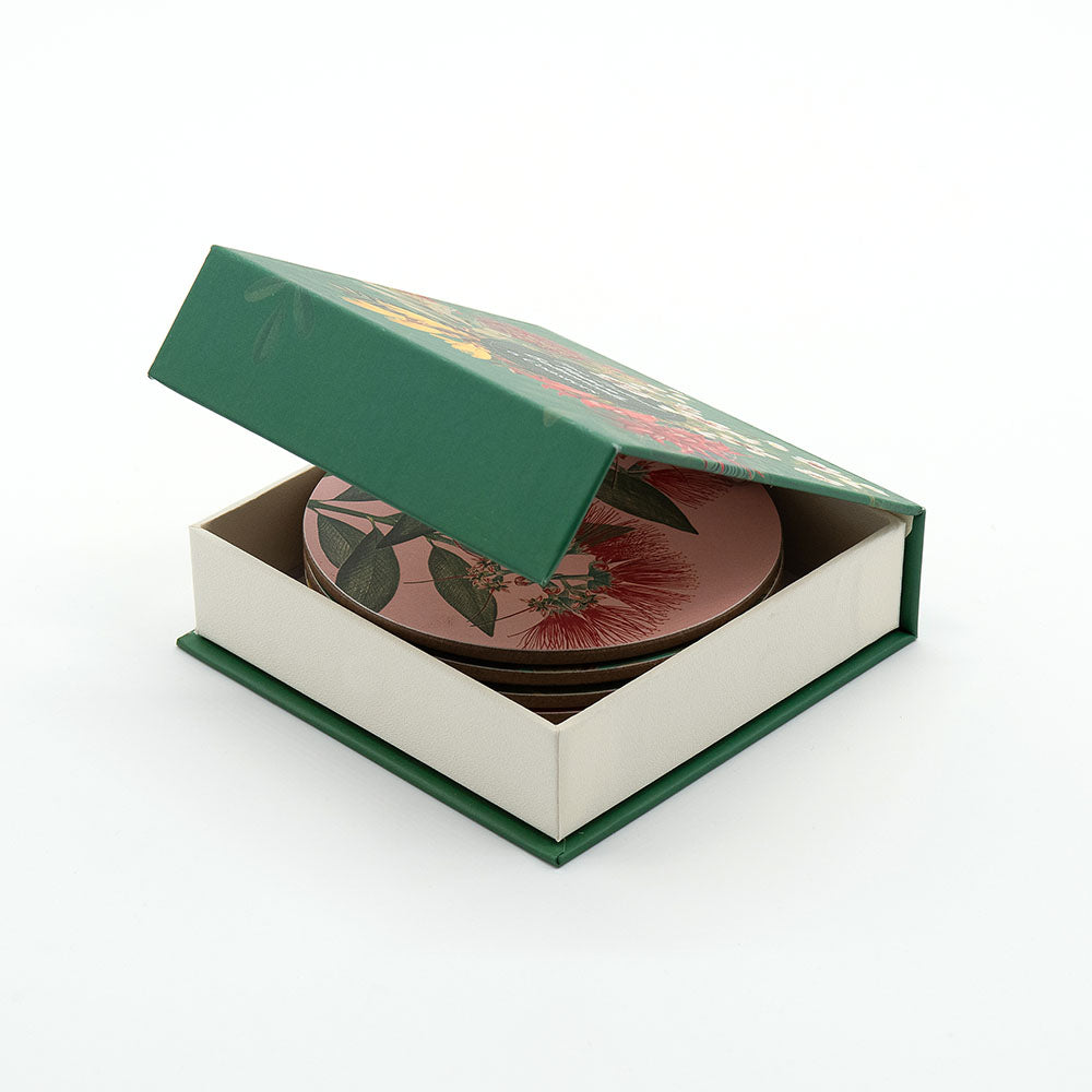 A green box with a floral lid, partially open to reveal the Native Botanicals of NZ set of 6 Coasters—round coasters inspired by New Zealand—displayed on a white background.