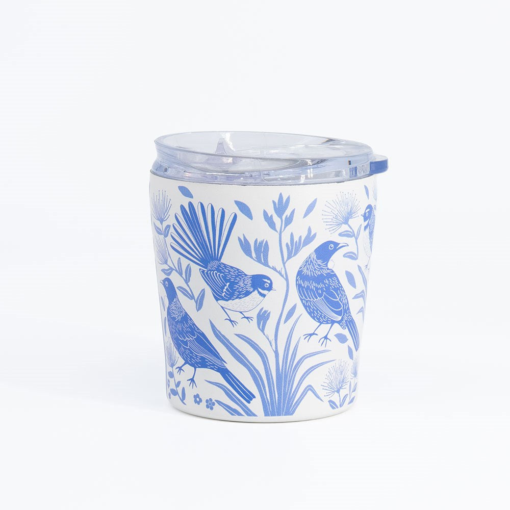 Introducing the Birdsong Blues Coffee Cup: a white, vacuum-insulated stainless steel travel mug featuring blue illustrations of birds and plants. It comes with a clear, spill-proof plastic lid and is shown against a simple, light background.