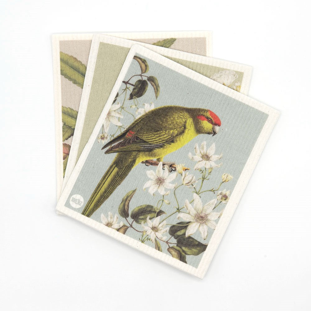 Three Swedish Dishcloths - Birds & Botanicals are stacked. The top cloth shows a yellow-green bird with a red patch on its head, perched among white flowers on an eco-friendly, light, muted background.