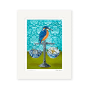 Angie Dennis - Fine Balance Art Print features a vibrant kingfisher on a balance scale with porcelain bowls holding silver fish and a gold insect, all set against a patterned turquoise background—ideal for NZ art lovers.