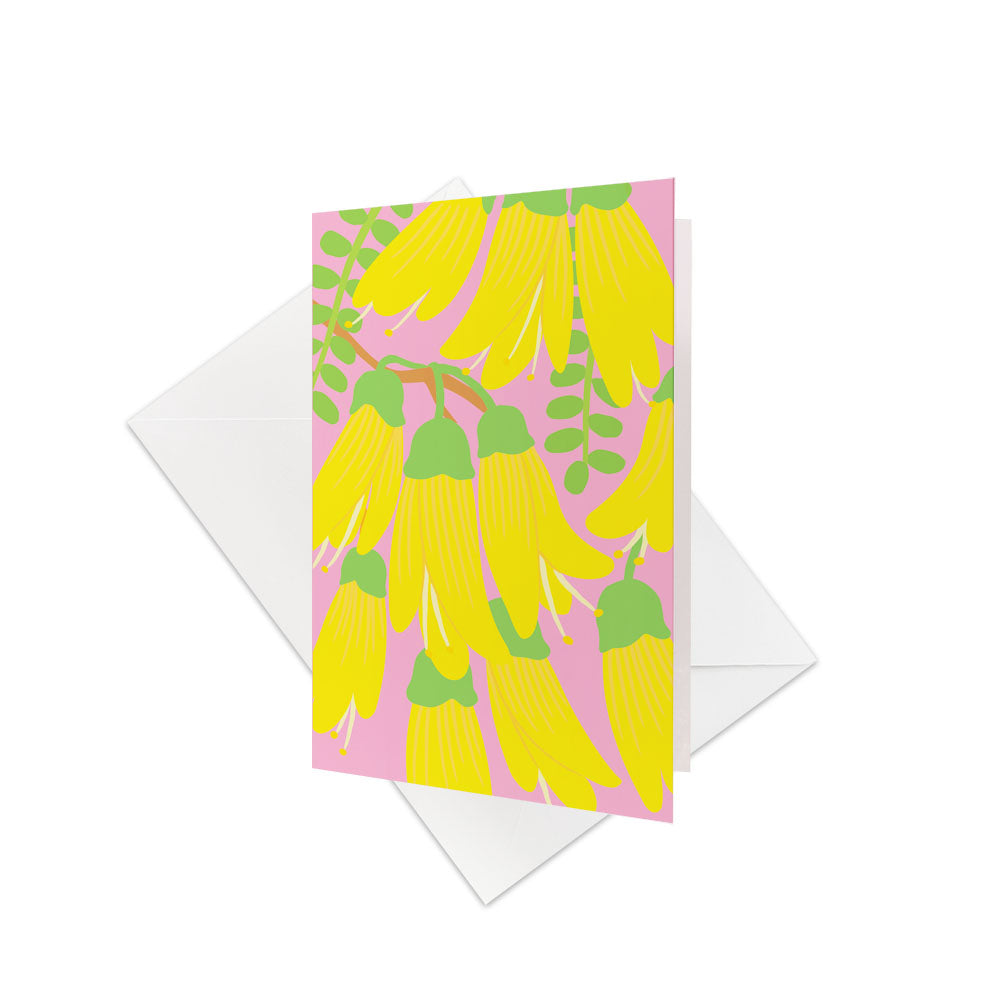 The Bright Botanical Kowhai Gift Card & Envelope (6 Pack) features vibrant yellow hanging Kowhai flowers with green stems and leaves on a pink background—a perfect, colorful way to present gift cards or send a personalised message. White envelopes included.