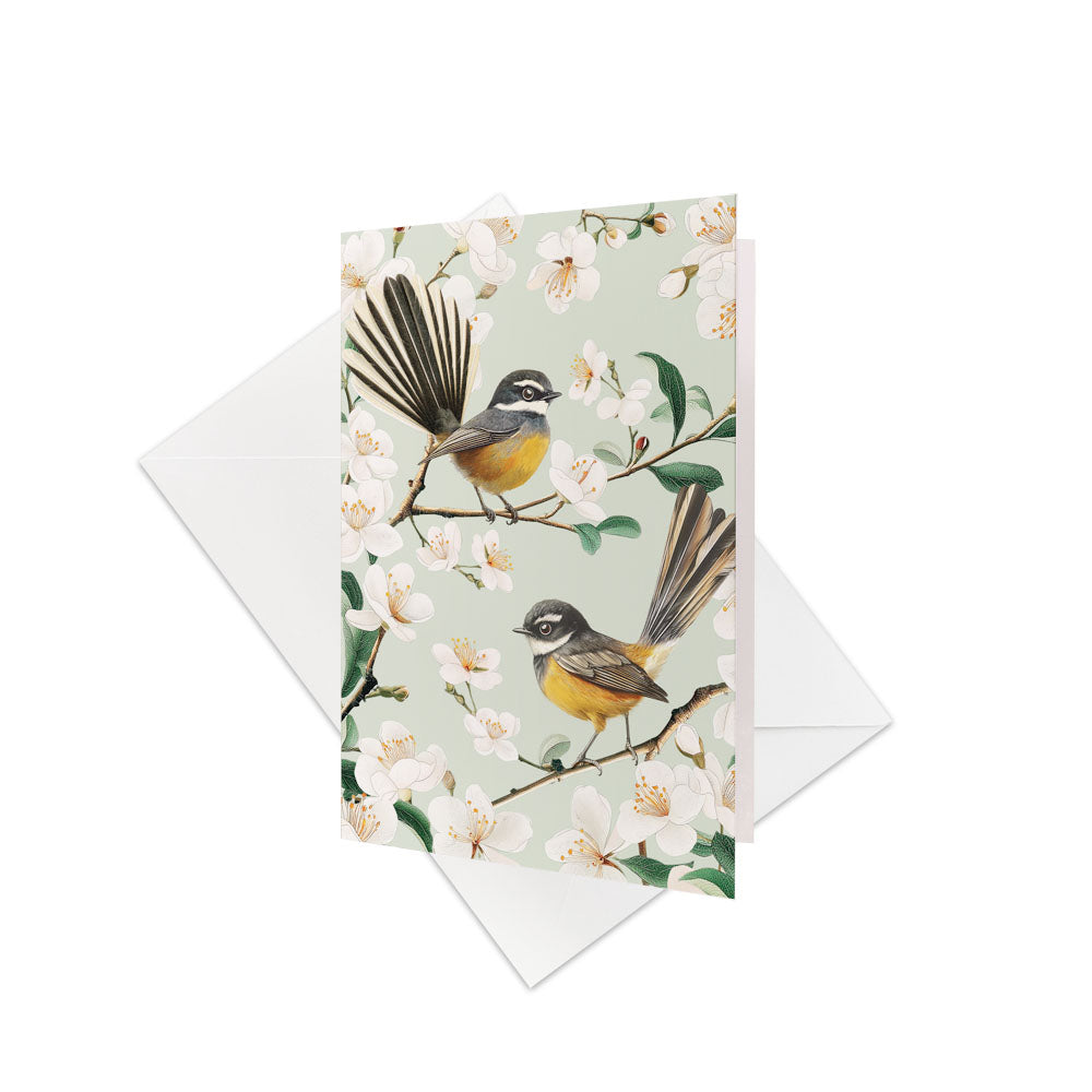 The Chatty Fantails Gift Card & Envelope (6 Pack) features two New Zealand native Fantails with yellow and gray feathers on flowering branches, set against a pale background—perfect for your personalised message.