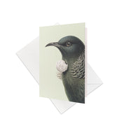 The Hushed Tui Gift Card & Envelope (6 Pack) features a beautifully illustrated Tūī, a striking bird native to New Zealand, with a white neck tuft, shown in front of a matching envelope on a plain white background.