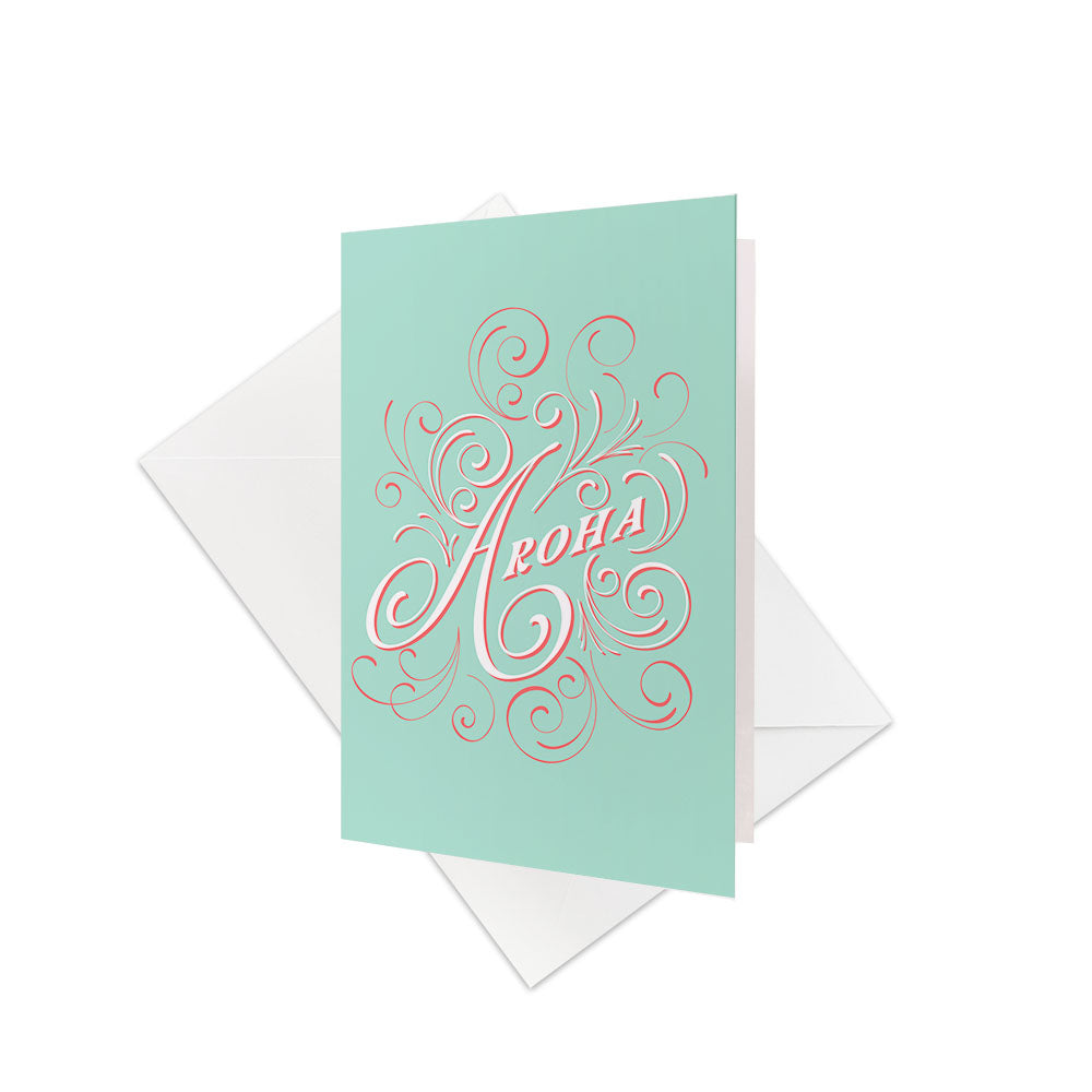 The Te Reo Aroha Gift Card & Envelope (6 Pack) features light blue cards with Aroha in bold, ornate script and decorative swirls, celebrating New Zealand Te Reo. Each card comes with a plain white envelope.