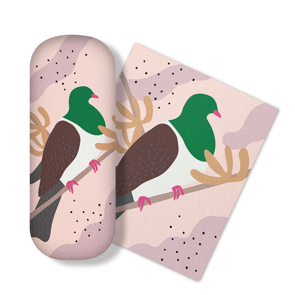 The Cut-out Kereru Glasses Case comes with a matching micro-fibre cloth, both featuring a stylized green and brown New Zealand bird with pink feet on a branch, set against a pink and beige abstract background.
