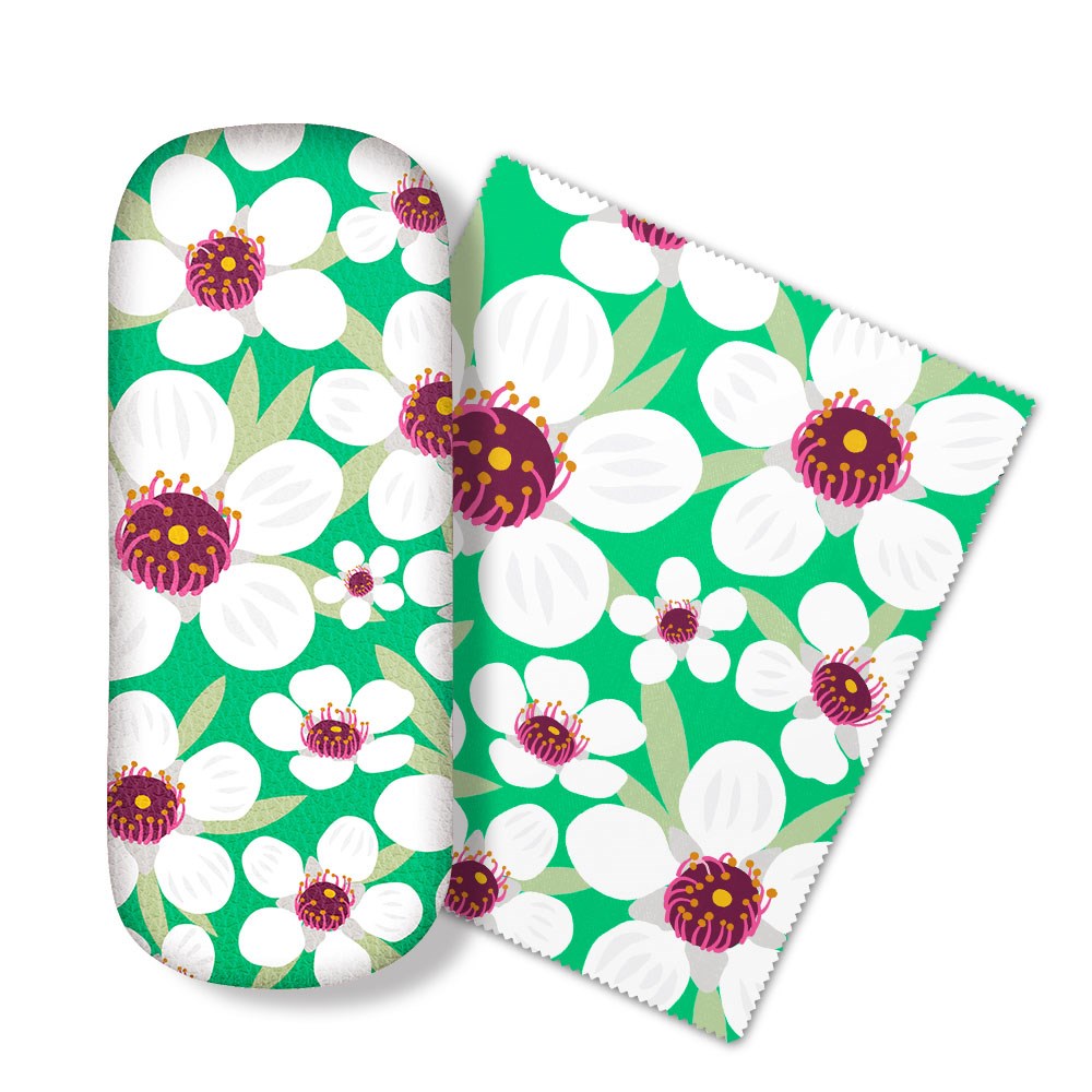 The Bright Botanical Manuka Glasses Case comes with a matching micro-fibre cloth and features a green design with white flowers, purple and yellow centers, and green leaves—perfect for cleaning your glasses in style.