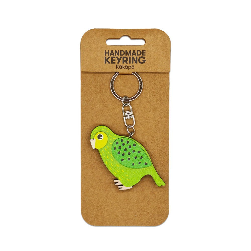 The Kakapo Wooden Keyring is a handmade green and yellow keychain with a silver chain and split ring, attached to a brown card labeled HANDMADE KEYRING Kakapo—a unique Kiwiana accessory.