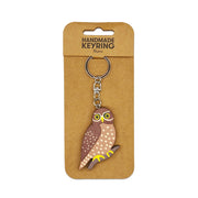 The Ruru Wooden Keyring is a handmade wooden keychain featuring a charming owl on a metal ring and chain, displayed on brown packaging labeled HANDMADE KEYRING Ruru—a unique Aotearoa keepsake.