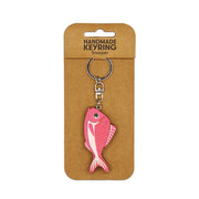 The Snapper Wooden Keyring is a pink, snapper-shaped wooden accessory with a metal clasp, attached to brown cardboard packaging labeled Handmade Keyring Snapper—a perfect handmade keychain for fish lovers.