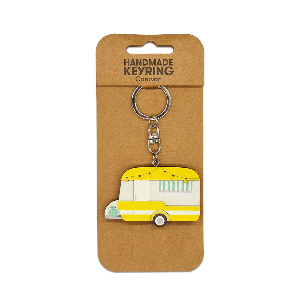 A yellow and white retro caravan design features on the Caravan Wooden Keyring, which is attached to brown cardboard packaging labeled Handmade Keyring Caravan in black text.