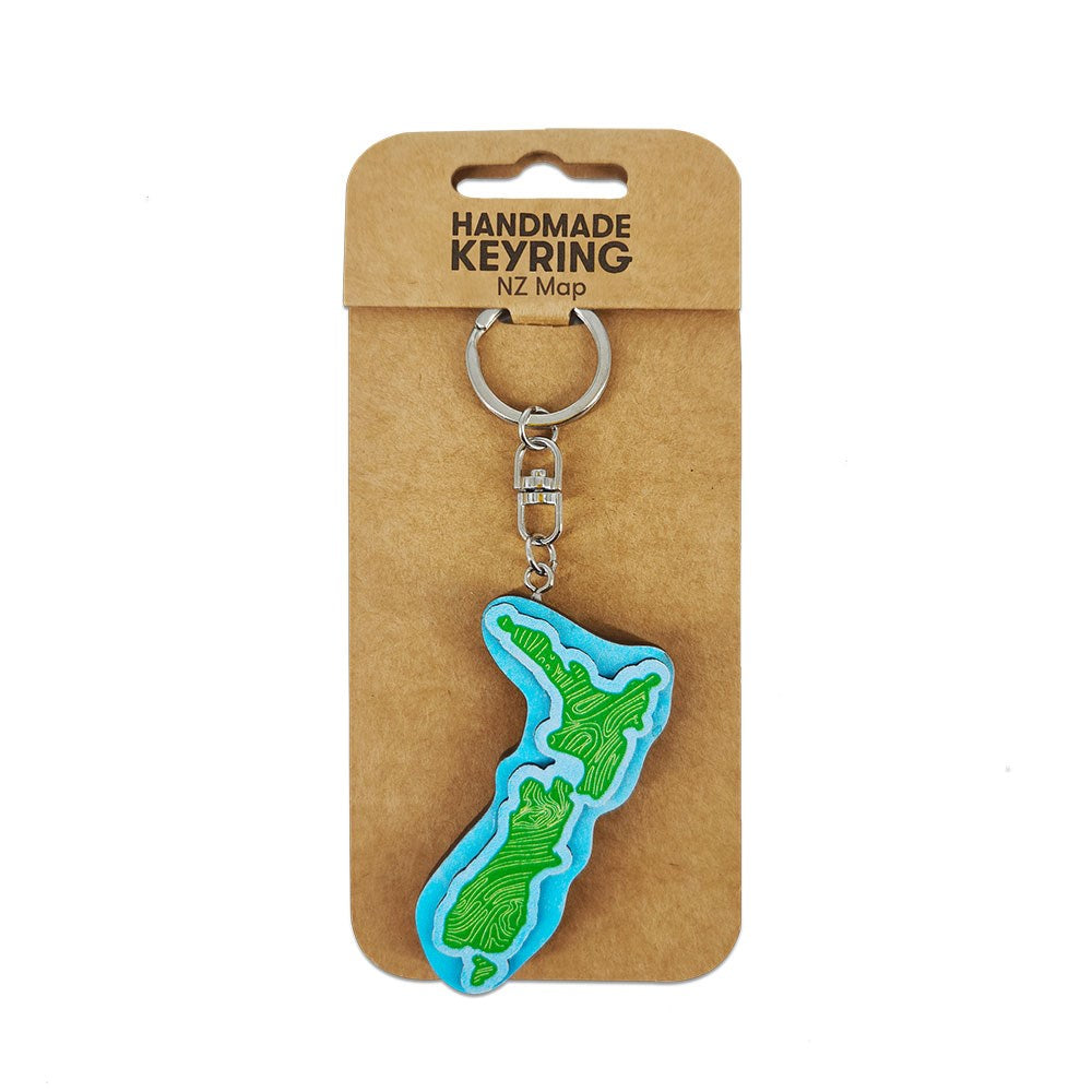 The NZ Map Wooden Keyring features a handmade New Zealand map design with green patterns and comes attached to packaging labeled Handmade Keyring NZ Map.