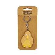 The Brown Kiwi Wooden Keyring is a wooden kiwi-shaped keyring attached to a metal chain, presented on a labeled brown cardboard backing—an ideal Aotearoa Keepsake and charming handmade accessory.