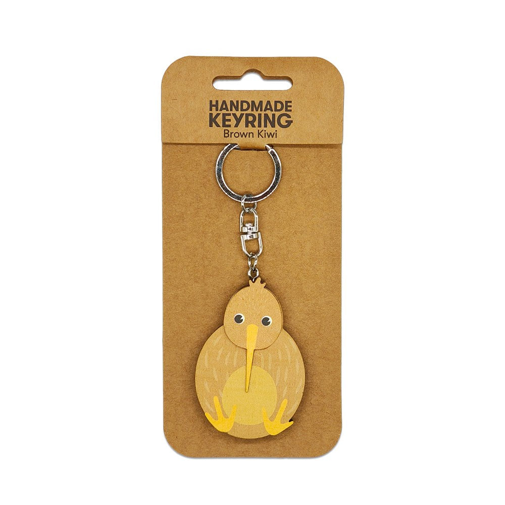 The Brown Kiwi Wooden Keyring is a wooden kiwi-shaped keyring attached to a metal chain, presented on a labeled brown cardboard backing—an ideal Aotearoa Keepsake and charming handmade accessory.