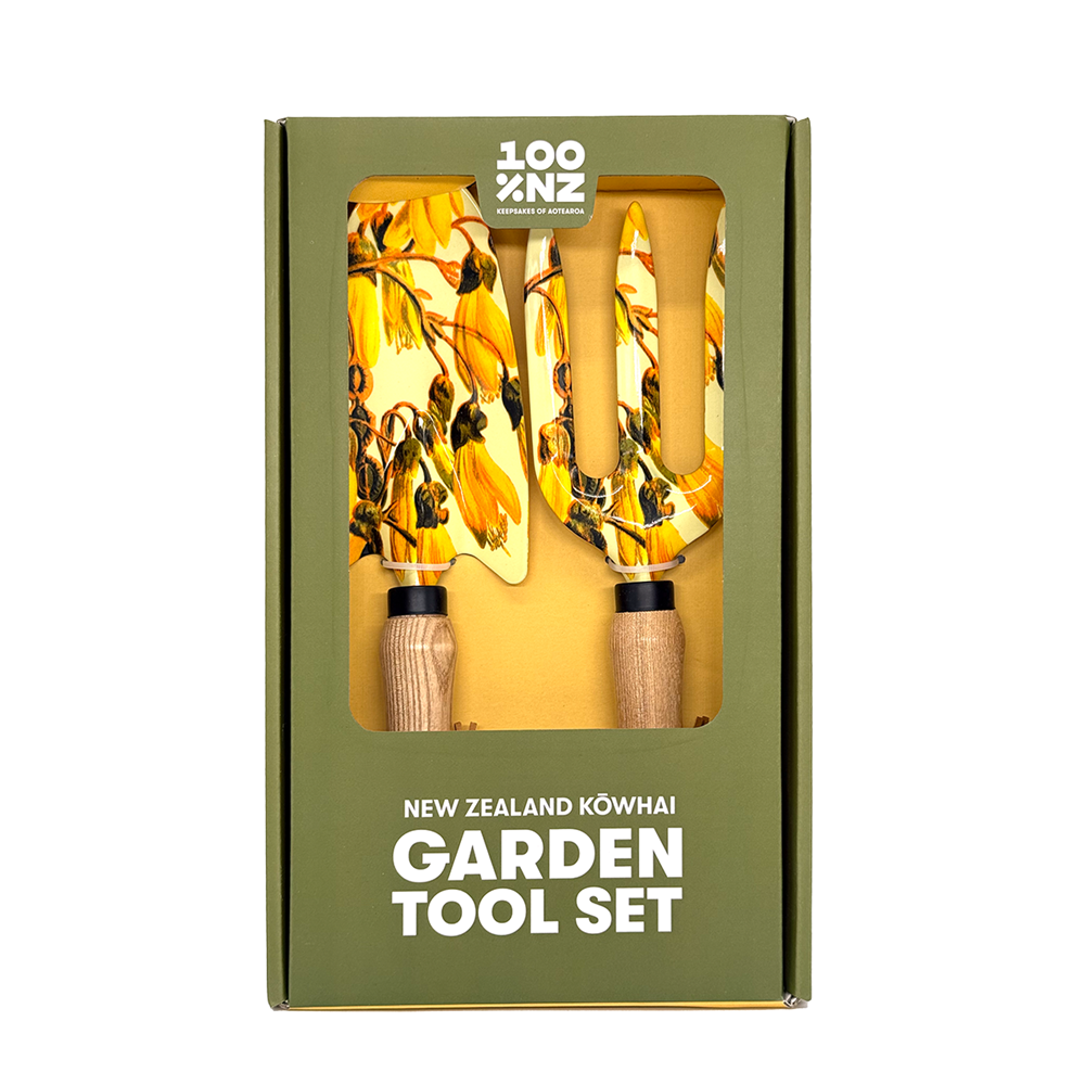 The NZ Kowhai Garden Tool Set includes ash wood-handled tools with metal heads featuring yellow New Zealand kōwhai flower designs, packaged in a green “100% NZ” branded box labeled “New Zealand Kōwhai Garden Tool Set.”.