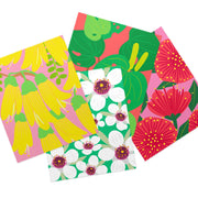 The Set of 4 Bright Botanical Collection Lens Cloths features rectangular cloths with colorful floral designs: yellow flowers on pink, green and red leaves, white flowers on green, and red flowers on pink backgrounds.