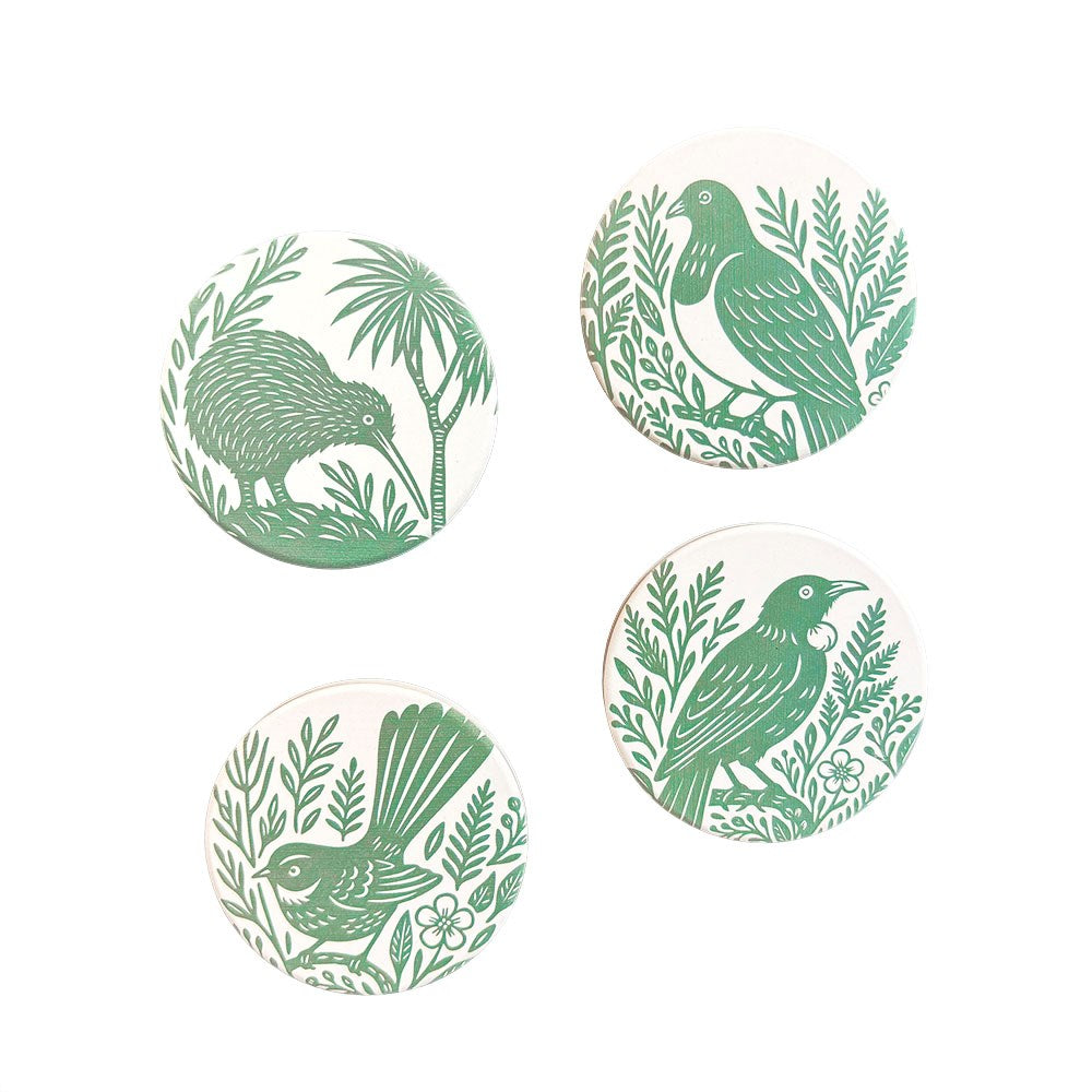 The Woodcut Ceramic Magnet Set includes four round magnets with unique green bird and plant designs on a white background, inspired by New Zealand nature—ideal as souvenirs or to enhance your printed ceramics collection.