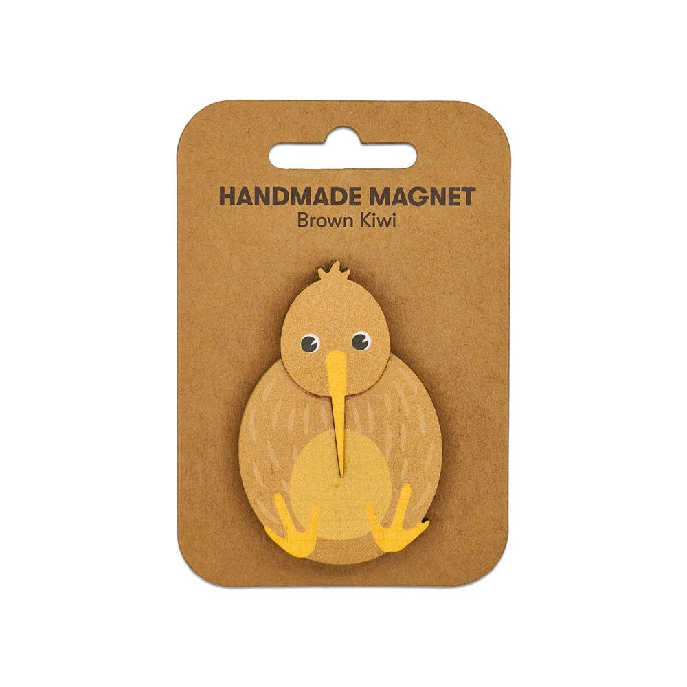 The Brown Kiwi Wooden Magnet is a handmade Kiwiana magnet shaped like a brown kiwi bird, featuring cartoon-like details, a yellow beak and feet, and comes attached to a card labeled Handmade Magnet Brown Kiwi.