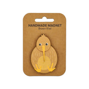 The Brown Kiwi Wooden Magnet is a handmade Kiwiana magnet shaped like a brown kiwi bird, featuring cartoon-like details, a yellow beak and feet, and comes attached to a card labeled Handmade Magnet Brown Kiwi.