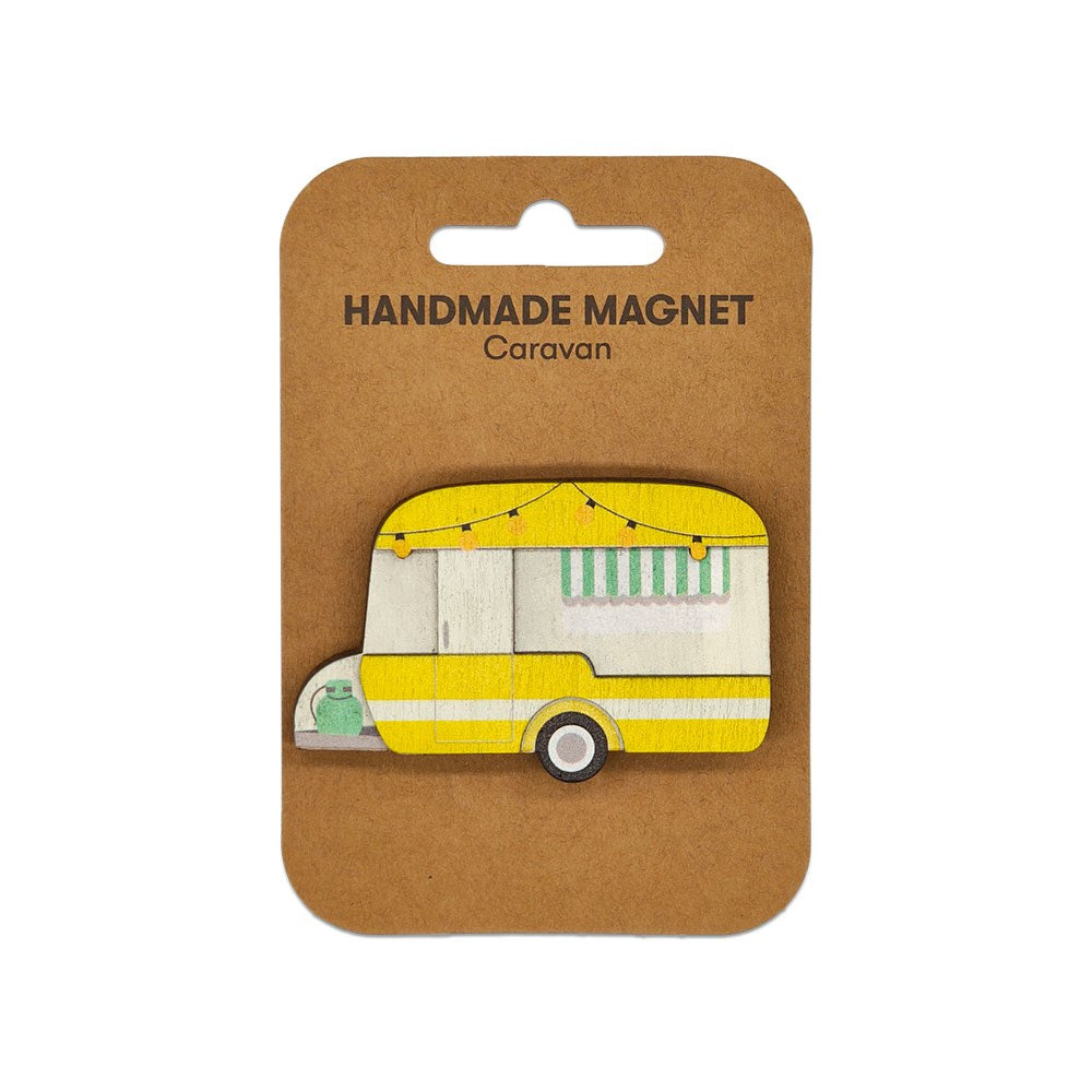 The Caravan Wooden Magnet is a handmade wooden magnet shaped like a yellow and white retro caravan, complete with striped awning and string lights. Attached to a brown card labeled Handmade Magnet Caravan. Great for any magnetic surface.