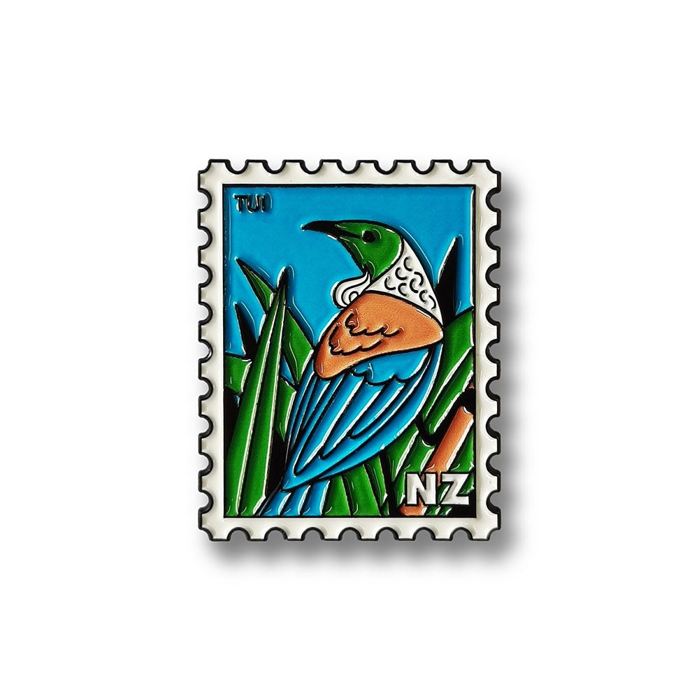 The Tui Collectible Stamp Magnet features Glenn Jones Artwork of a stylized Tui with blue, green, and white feathers among leaves, shaped like a postage stamp and marked with NZ in the lower right corner.