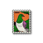 The Kereru Collectible Stamp Magnet features Glenn Jones Artwork of a kererū bird with a green head, white belly, and purple wings on an orange background with green leaves, labeled KERERU and NZ—a unique collectible.