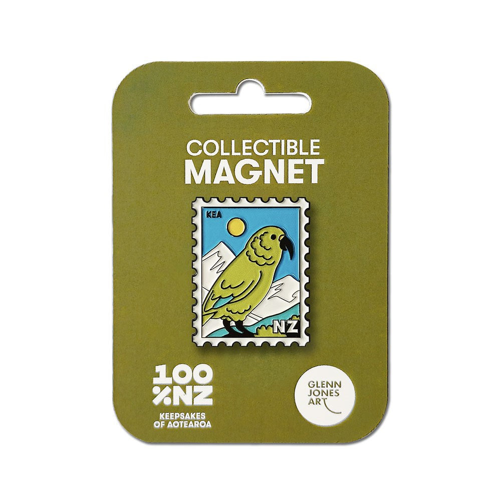 A rectangular Kea Collectible Stamp Magnet showcases Glenn Jones Artwork of a green Kea parrot, mountains, and a yellow sun on olive-green packaging labeled Collectible Magnet and 100% NZ.