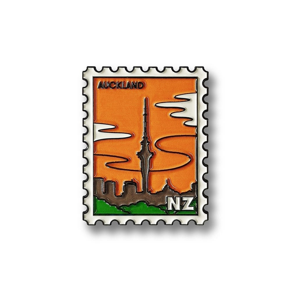 The Auckland Collectible Stamp Magnet features a stylized postage stamp design with the citys skyline and Sky Tower silhouette. AUCKLAND appears at the top and NZ at the bottom right, inspired by Glenn Jones Artwork.