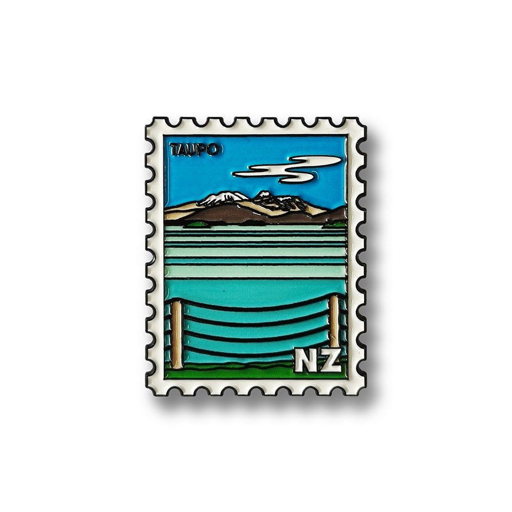 A stylized postage stamp illustration by Glenn Jones depicts Lake Taupo, NZ, with blue water, mountains, and a fence—featured on the Taupo Collectible Stamp Magnet.