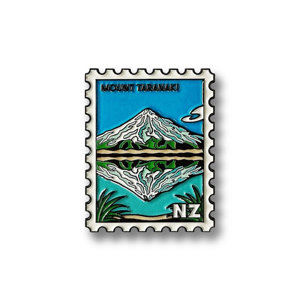 A stylized Glenn Jones illustration shows Mount Taranaki mirrored in water, with blue sky, green foliage, and “NZ” on the stamp—captured perfectly in the Mt Taranaki Collectible Stamp Magnet.