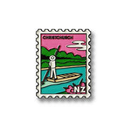 A magnet styled as a postage stamp features a cartoon figure on a boat in a river, pole in hand, with green trees and pink sky. Text reads CHRISTCHURCH and NZ—an iconic Glenn Jones Artwork Christchurch Collectible Stamp Magnet.