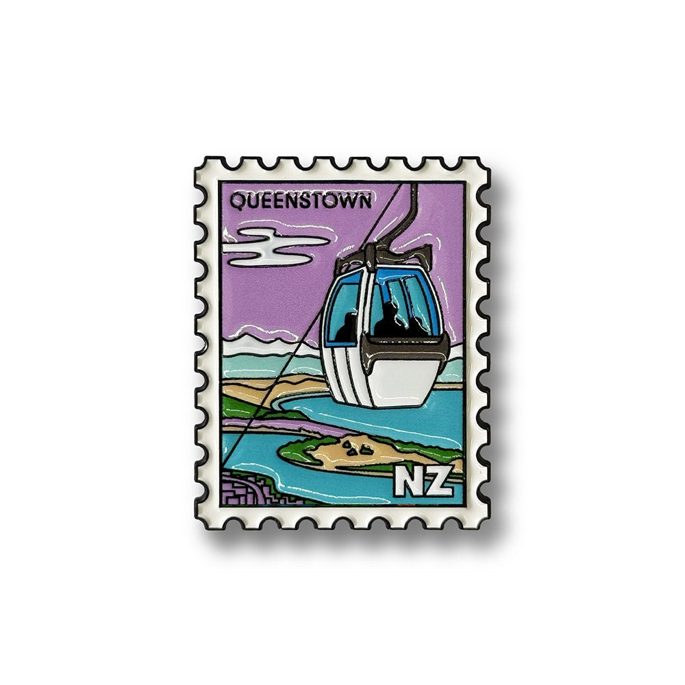 The Queenstown Gondola Collectible Stamp Magnet features a postage stamp illustration of the iconic gondola overlooking water, lush green landscapes, and rolling hills. "QUEENSTOWN" is displayed at the top, while "NZ" appears in the bottom right corner. Set against a purple background with clouds, this enamel magnet beautifully captures a scenic moment from New Zealand.