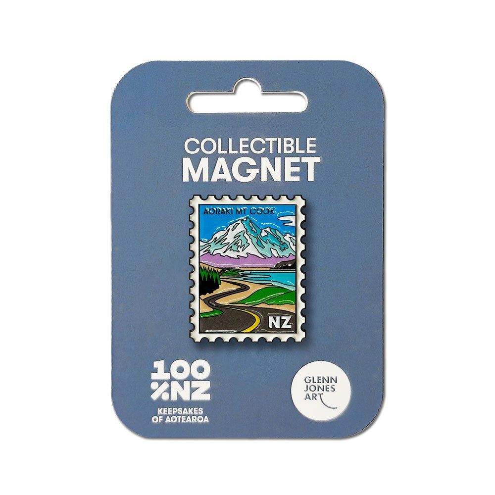 The Aoraki Mt Cook Collectible Stamp Magnet is a rectangular enamel magnet shaped like a postage stamp, featuring a vibrant New Zealand landscape with Aoraki Mt Cook, a winding road, and "NZ" in the corner. It comes on blue packaging labeled "Collectible Magnet.